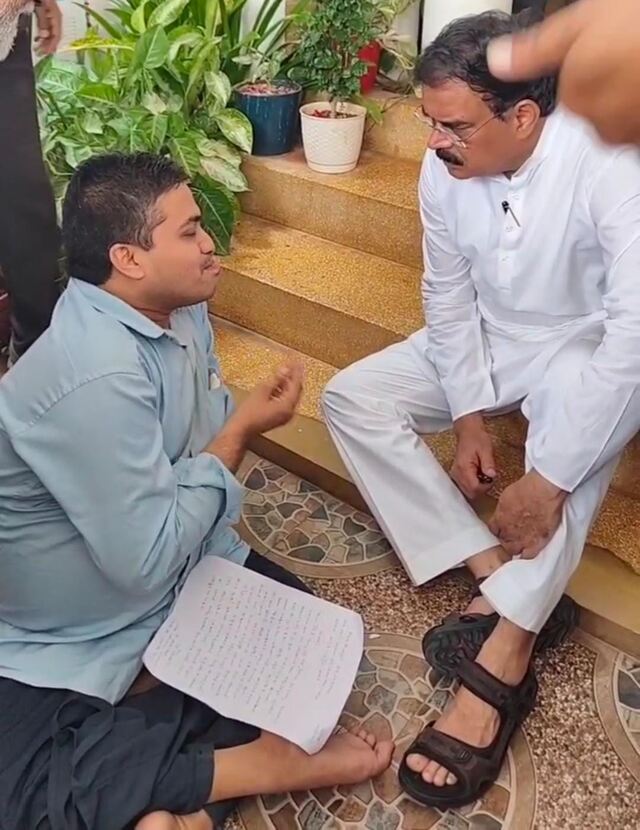 దివ్యాంగుడి కోసం నేలపై మంత్రి!